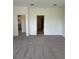 Open-concept living room featuring neutral walls, carpet and multiple doorways at 6107 Sw 115Th Street Rd, Ocala, FL 34476