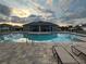 Beautiful community pool area featuring a shimmering pool, comfortable loungers, and a sunset sky at 2374 Aquiline Nest St, Eagle Lake, FL 33839