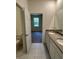 Bathroom with dual sinks, granite countertops and tile flooring with view into the bedroom at 5530 Sw 103Rd St Rd, Ocala, FL 34476