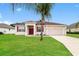 Single-story home with red door, two-car garage, and landscaped lawn at 5634 Moon Valley Dr, Lakeland, FL 33812