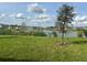 Scenic backyard view with a serene pond, mature landscaping, and distant houses under a cloudy sky at 999 Brooklet Dr, Davenport, FL 33837