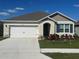 Inviting single-story home with a two-car garage, manicured lawn, and colorful shrubs at 999 Brooklet Dr, Davenport, FL 33837