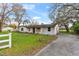Single-story home featuring a white painted brick exterior, mature trees and large front yard at 3800 Levins Rd, Mulberry, FL 33860