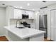Modern kitchen featuring white cabinets, stainless steel appliances, and a large quartz countertop island at 26922 White Plains Way, Leesburg, FL 34748