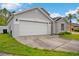 Gray home showcasing a two-car garage, green lawn, and front yard, with ample parking space at 580 Tree Shore Dr, Orlando, FL 32825