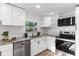 This all-white kitchen boasts stainless steel appliances, granite countertops, and a modern design at 760 S Park Ave, Winter Garden, FL 34787