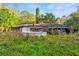 View of the overgrown backyard with above-ground pool and dated deck at 1915 Poinsettia Dr, Port Orange, FL 32128