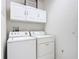 Efficient laundry room with washer, dryer, and ample storage cabinets above at 3514 Yacht Club Ct, Kissimmee, FL 34746