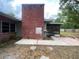 View of the exterior brick chimney and enclosed patio from the spacious backyard at 5801 Poinciana Ave, Lakeland, FL 33809