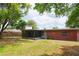 Wide shot of the home's backyard, showing grass, trees, fence, and enclosed patio at 5801 Poinciana Ave, Lakeland, FL 33809