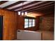 Living room featuring beamed ceilings, paneled walls, and a stone accent wall with a large window at 5801 Poinciana Ave, Lakeland, FL 33809