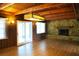 Cozy living room with wood paneled walls, beamed ceiling, stone fireplace, and sliding glass doors at 5801 Poinciana Ave, Lakeland, FL 33809