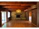 Living room with wood paneled walls, beamed ceiling, stone fireplace, and sliding glass doors to the lanai at 5801 Poinciana Ave, Lakeland, FL 33809