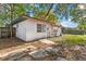 Exterior shot of a backyard with overgrown leaves, grass, and a glimpse of the white house under a blue sky at 1586 Fergason Ave, Deltona, FL 32725