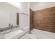 Bathroom showcasing white cabinetry, granite countertops, and a bathtub with wood-style tile surround at 421 Arkansas Ct, Poinciana, FL 34759
