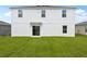 A view of the back of a two-story house with a sliding glass door and a green lawn at 2222 Oklahoma Dr, Sumterville, FL 33585