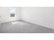 Bright bedroom featuring neutral carpeting, white walls, and a large window with natural light at 2222 Oklahoma Dr, Sumterville, FL 33585