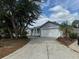 A single-Gathering home with a long driveway flanked by mature trees and landscape at 1152 Mccormick Dr, Deltona, FL 32725