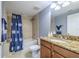 Bright bathroom featuring a granite countertop, wood cabinets, and a shower-tub combo with blue curtain at 2071 S Atlantic Ave # 201, Daytona Beach Shores, FL 32118