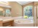 Bathroom with large tub under an arched window with view of lush landscape at 5701 John Anderson Hwy, Flagler Beach, FL 32136