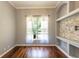 Bedroom featuring a built-in shelf, hardwood floors, and a window overlooking a landscaped yard at 5701 John Anderson Hwy, Flagler Beach, FL 32136