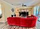 Comfortable living room featuring a plush red sofa, ceiling fan, and sliding glass door access at 28 Dormer Dr, Ormond Beach, FL 32174