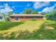 A well-kept lawn and the rear exterior of a brown home under a bright blue sky with scattered clouds at 1119 Indigo Rd, Ormond Beach, FL 32174