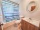 This bathroom features a sink with cabinets and a bathtub with a striped shower curtain at 1119 Indigo Rd, Ormond Beach, FL 32174