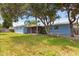 Spacious, grassy backyard featuring the house with a screened-in patio on a sunny day with plenty of green trees at 10 Juniper Dr, Ormond Beach, FL 32176
