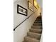 Carpeted staircase with a black handrail and decorative artwork, showcasing elegant design at 64 Ocean Palm S Dr # 64, Flagler Beach, FL 32136