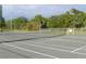Outdoor tennis court surrounded by lush green trees and fencing at 64 Ocean Palm S Dr # 64, Flagler Beach, FL 32136