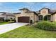 Tan two-story house with brown garage door and landscaping at 3242 Bailey Ann Dr, Ormond Beach, FL 32174