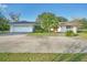 Single story home with white exterior, attached garage, and palm trees at 1045 Carter Rd, Deland, FL 32724