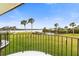 Balcony view showcasing a green lawn, palm trees, and a waterfront setting under a blue sky at 66 Ocean Palm Villa S, Flagler Beach, FL 32136