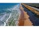 Expansive beach view with ocean waves meeting the sandy shore alongside a road and vegetation at 66 Ocean Palm Villa S, Flagler Beach, FL 32136