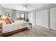 Bedroom with light hardwood floors, a ceiling fan, and large windows overlooking a grassy area with palm trees at 66 Ocean Palm Villa S, Flagler Beach, FL 32136