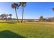 Expansive green lawn with palm trees overlooking a serene waterfront view, offering a peaceful outdoor setting at 66 Ocean Palm Villa S, Flagler Beach, FL 32136