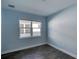 Light blue bedroom with large window and wood-look floors at 707 Hang Loose Way, Daytona Beach, FL 32124