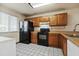 Galley kitchen with wood cabinets, black appliances, and tiled floor at 3548 Forest Branch Dr # C, Port Orange, FL 32129