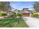 Tan two-story house with brown garage door and lush landscaping at 3238 Bailey Ann Dr, Ormond Beach, FL 32174