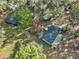 Aerial view of a house with a deck and a separate structure, all surrounded by mature trees at 7024 Sw 93Rd Street Rd, Ocala, FL 34476