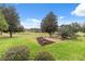 Landscaped backyard with manicured lawn, mature trees, and a stone garden at 4546 Nottoway Dr, Leesburg, FL 34748