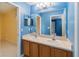 Clean bathroom with double vanity, light blue walls, and a large mirror at 4546 Nottoway Dr, Leesburg, FL 34748