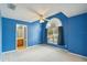 Bright bedroom with blue walls, carpet flooring, ceiling fan, and an arched window at 4546 Nottoway Dr, Leesburg, FL 34748