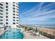 Oceanfront pool with patio furniture and a white building in the background at 1415 Ocean Shore Blvd # H040, Ormond Beach, FL 32176