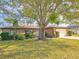 Brick home with a large tree in the front yard and well-manicured lawn at 840 Chickadee Dr, Port Orange, FL 32127