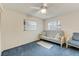 Bright bedroom with blue carpet, white futon, ceiling fan, and windows with blinds at 812 Whiporwill Dr, Port Orange, FL 32127