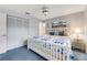 Bedroom features blue carpeting, a floral-patterned bed, a ceiling fan, and an ensuite bathroom at 812 Whiporwill Dr, Port Orange, FL 32127
