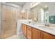 Bathroom featuring double sinks, a large mirror with vanity lights, and a glass-enclosed tiled shower at 820 Aldenham Ln, Ormond Beach, FL 32174