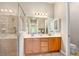 Bathroom with double sinks, a large mirror with vanity lighting, and a glass-enclosed tiled shower at 820 Aldenham Ln, Ormond Beach, FL 32174